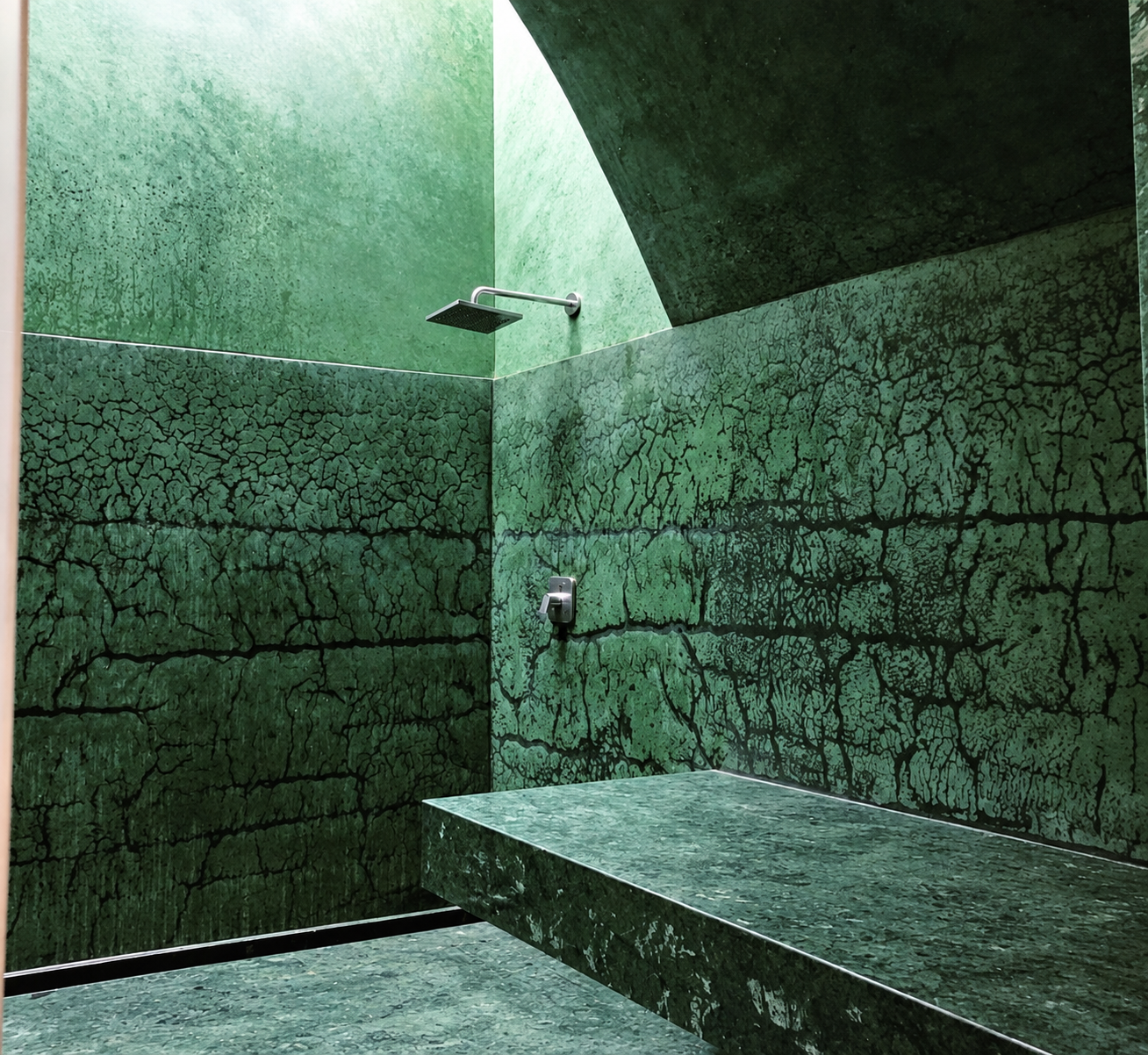 Hammam aux surfaces vertes texturées, avec banquette et douche intégrée